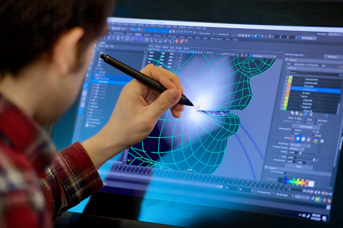 A worker using a digital pen on a screen designing a face